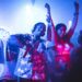 Festivals été 2025 : Deux jeunes, hommes et femmes, dansent au sons de la musique d'un dj dans une boîte de nuit sous une lumière bleue nuit.